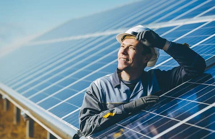 Artisan solaire observant un champ de panneaux photovoltaïques
